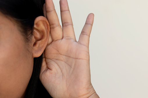 woman listening  hand close to ear.