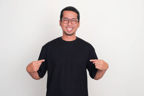 istock A man smiling at the camera while pointing to plain black t-shirt that he wearing 1971622206