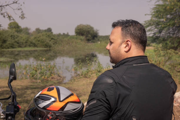 istock Indian biker taking a break looking out at a lake with birds 1971724434
