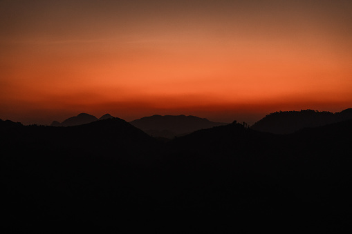 Mountains outline on the background of orange sky in sunrise/sunset