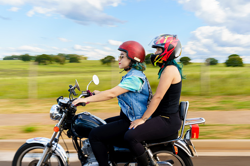 Motorcyclist and passenger riding a motorcycle on a road during a trip.