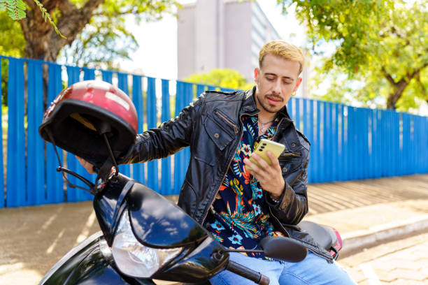 istock Man in black leather jacket sitting on his motorcycle using cell phone during rest stop 1971778825