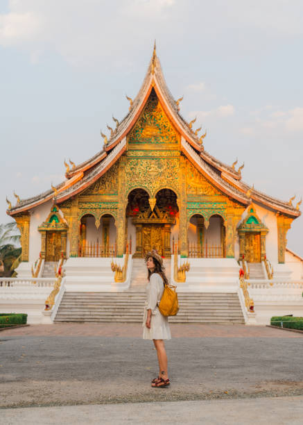Woman exploring buddhist temple in Laos  at sunrise