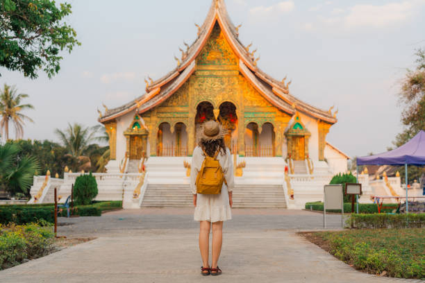 Woman exploring buddhist temple in Laos  at sunrise