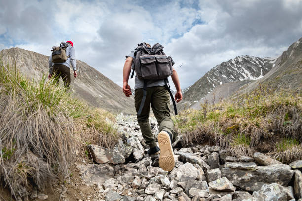 Two active hikers with backpacks walks in mountains