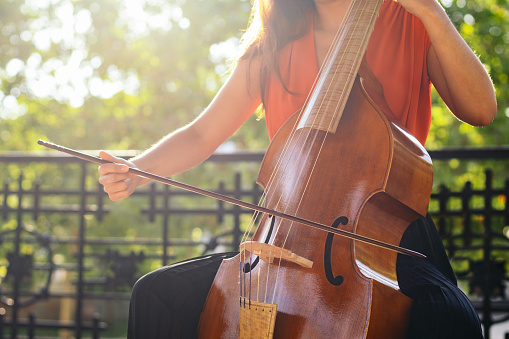 Outdoor string concert. A woman plays the cello in an old music kiosk in a garden