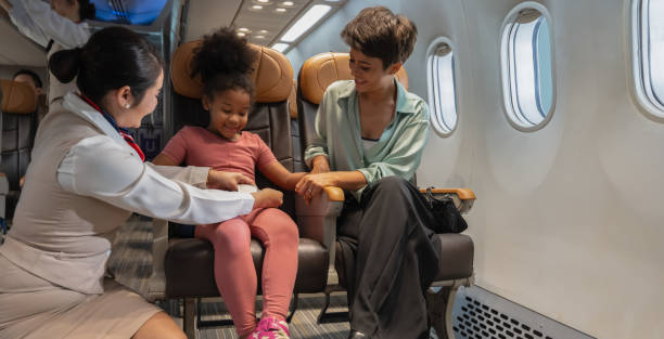 istock Friendly flight attendant take car kid passenger on board. Cabin crew helping curly African girl to faster her seat belt 1971854211
