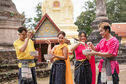 Young Thai people dress in traditional Thai costumes and play in the water during Songkran.