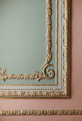 Gilded reliefs adorn the wall, which is painted in a combination of green and pink hues.