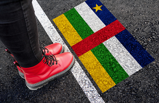 a woman with a boots standing on asphalt next to flag of Central African Republic and border