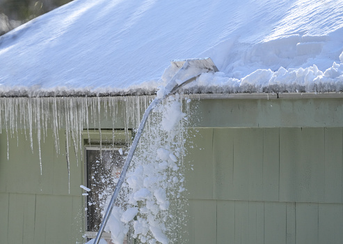 removing snow and icicle on the roof after snow storm