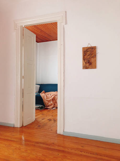 une maison grecque à haut plafond, avec vue sur une porte de salon ouverte révélant un fauteuil et une couverture. banque d’images - high ceilinged photos et images de collection