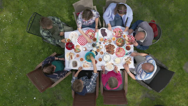 Drone aerial view of multi-generation family enjoying garden party celebration meal together