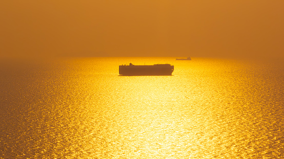 Aerial view Roll on Roll off vehicle car carrier, Seascape over colorful and silhouette Roll on Roll off vehicle car carrier floating in sea in the golden hour time,