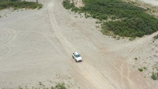 Aerial view of a car driving on sand in summer
