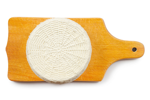 A circle of cheese on a wooden cutting board. Homemade cheese on a white background. Natural organic cheese made from milk.