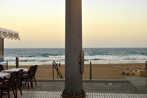 Gran Canaria, Canary Island of Spain - January 26, 2024: concrete column in middle. Left pizzeria sidewalk café in front of the beach Maspalomas