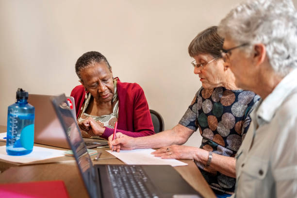 istock Senior teacher discussing studies with senior female students in office 1972025366