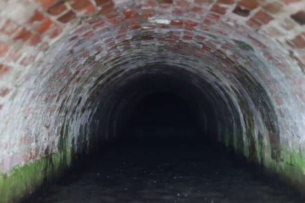 Dirty urban sewage flowing through rectangular sewer tunnel under Moscow.