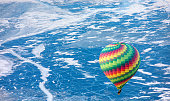 Hot air balloon flying over Ogoy island on winter Baikal lake with transparent cracked blue ice at sunrise - Baikal, Siberia, Russia