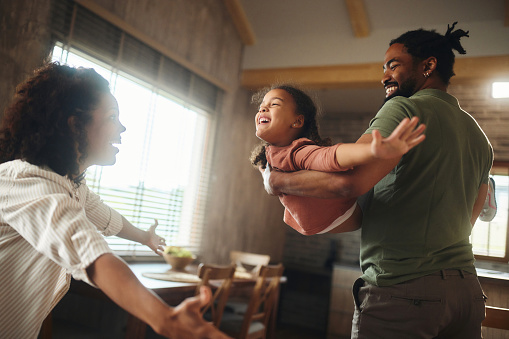 Happy African American parents having fun with their small girl at home.