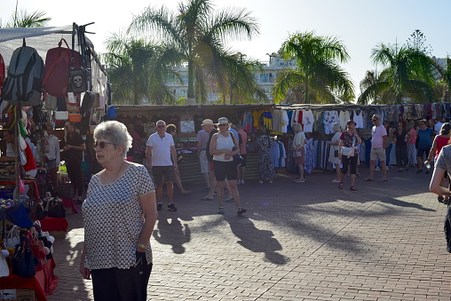 Gran Canaria, Canary Island of Spain - January 27, 2024: Western European tourists walking between Spanish market stalls under a mediterranean climate in Winter