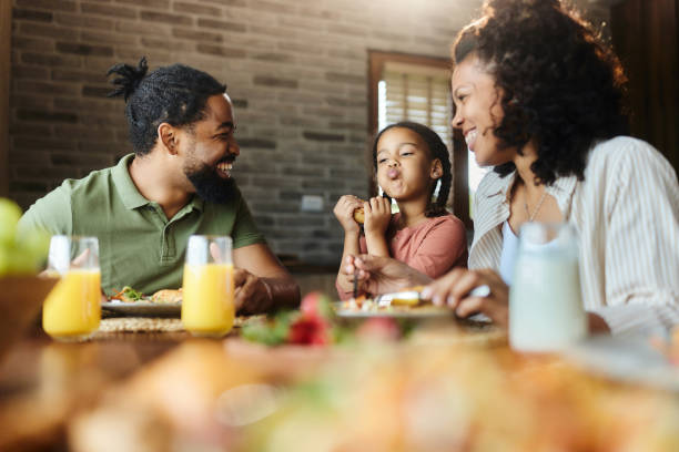 istock Cute black girl having fun with her parents during breakfast at dining table. 1972044758