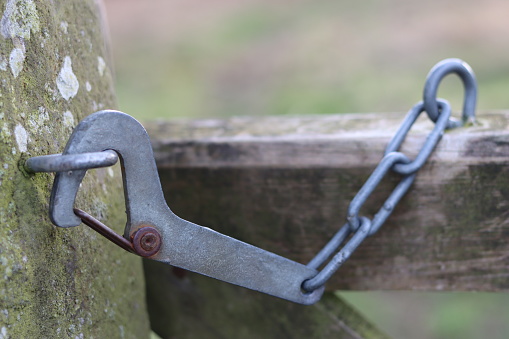 Closed gate on a footpath, secured by an old metal hook latch