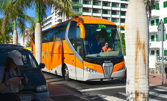 Gran Canaria, Canary Island of Spain - January 27, 2024: public orange color Canary shuttle brand Man bus arriving at hotel in Maspalomas coming from airport to Las Palmas