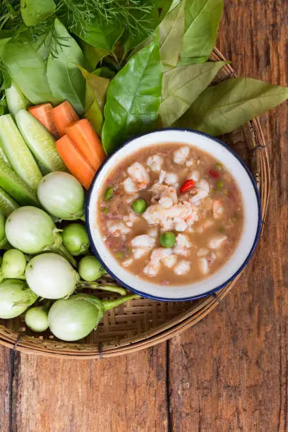 Photo of Shrimp Paste Chilli Sauce (Nam Prik Jone) served with fresh Vegetable on wood table, top view, Traditional Thai southern food, Thai food concept and healthy food style.