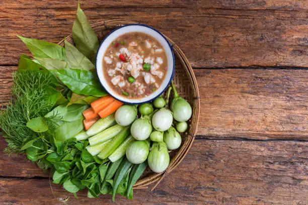 Photo of Shrimp Paste Chilli Sauce (Nam Prik Jone) served with fresh Vegetable on wood table, top view, Traditional Thai southern food, Thai food concept and healthy food style.