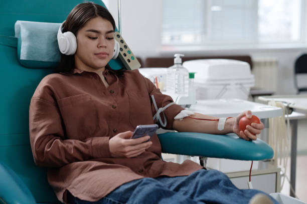mulher jovem relaxada sentada na poltrona durante o procedimento de doação de sangue - pumping blood audio - fotografias e filmes do acervo