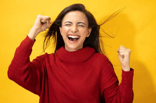 Photo of young women in winter wear standing on yellow background