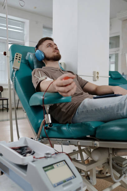 homem branco jovem sentado na poltrona durante a transfusão de sangue - pumping blood audio - fotografias e filmes do acervo