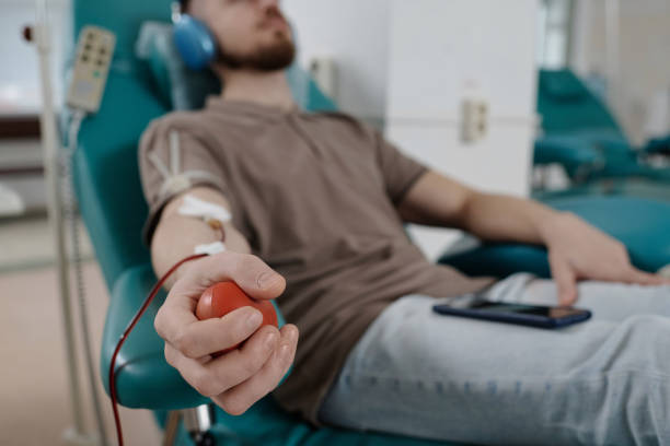 doador de sangue masculino segurando bola de borracha sentado na cadeira médica - pumping blood audio - fotografias e filmes do acervo