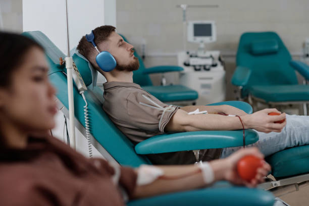 病院で献血しながらリラックスする若者たち - pumping blood audio ストックフォトと画像