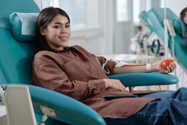 donneuse de sang joyeuse assise sur une chaise d’intervention dans une clinique - don du sang photos et images de collection