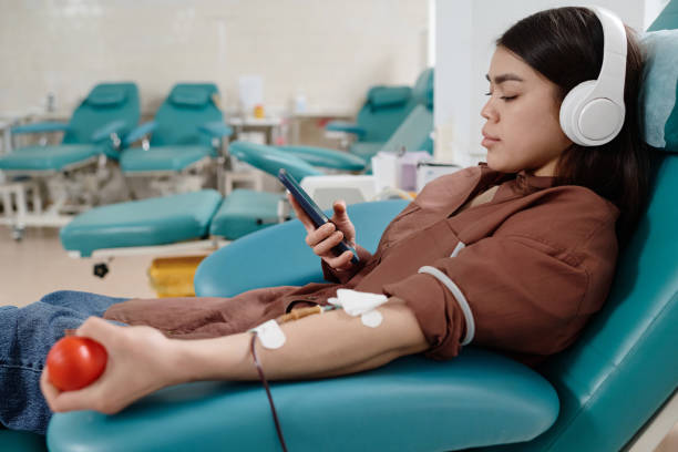 献血中にスマートフォンで情報を確認する女性 - pumping blood audio ストックフォトと画像