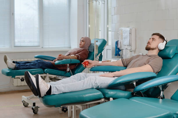 visitantes do centro médico doando sangue deitados em cadeiras de procedimentos - pumping blood audio - fotografias e filmes do acervo