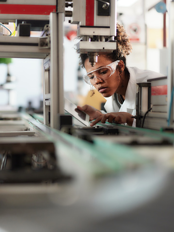 African American female scientist using digital tablet while working on production line in laboratory.