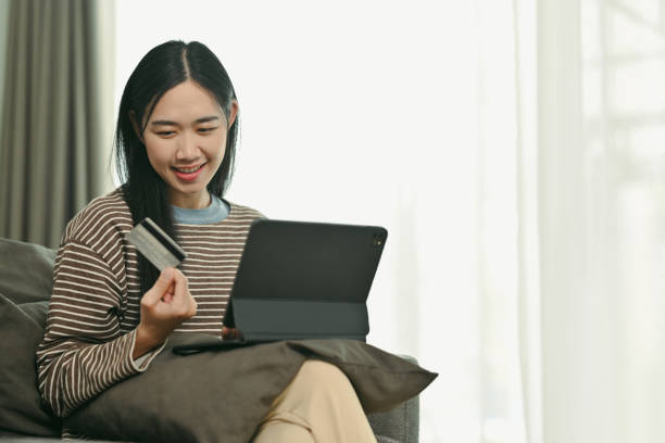 istock Charming young woman holding credit card making payment on digital tablet 1972103438