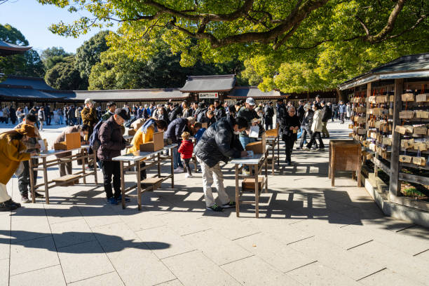 Tokyo, Japan. January 8, 2024. the faithful as they write the Ema tablets, wooden plaques on which the faithful write the wishes to be addressed to the spirits, hanging at the Meiji Shinto shrine.