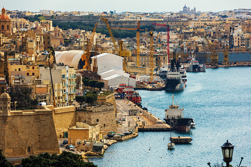 View of old medieval city walls and cargo ships in the harbor of Valletta, Malta.