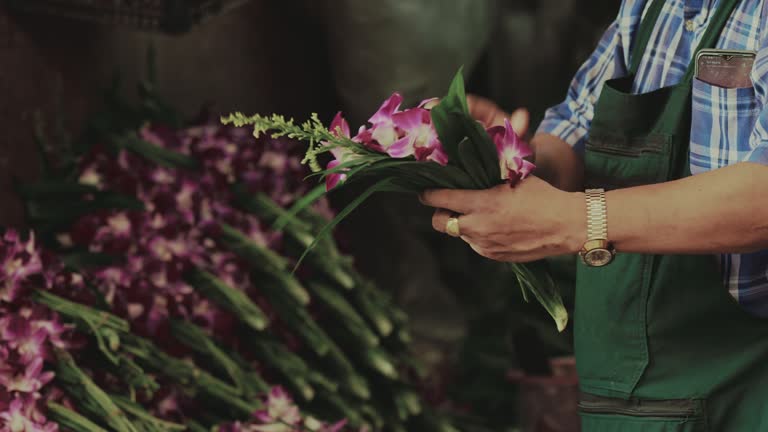 A merchant's hands tie purple orchids