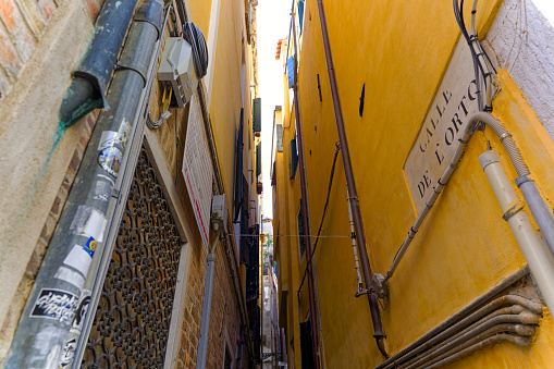 Narrow alley at the old town of Venice with facades of historic houses on a sunny summer day. Photo taken August 7th, 2023, Venice, Italy.