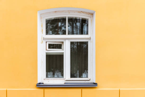 istock Arched window with white wooden frame in yellow wall 1972160405