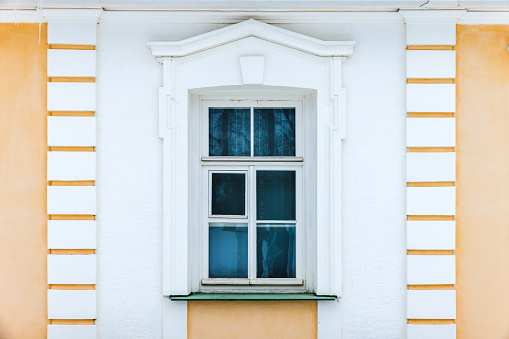 Classic architecture details, background photo texture. Window with white frame in yellow stone wall