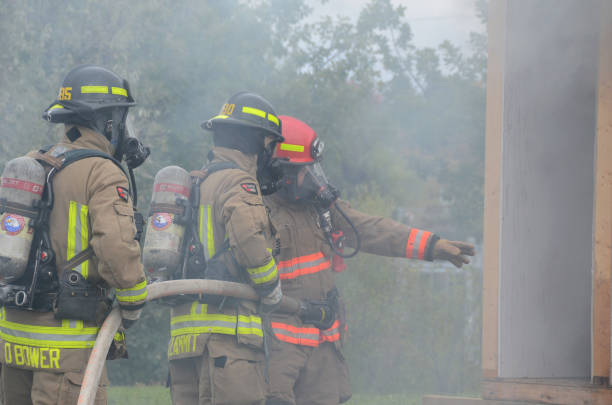 A firefighter run through Water mist and heavy smoke holding a rescue axe during an emergency response drill