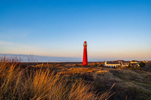 Schiermonnikoog panoramic view in the dunes with the lighthouse during sunset at the wadden island during a beautiful winter day. Schiermonnikoog is part of the Frisian Wadden Islands and is known for its beautiful natural scenery, including sandy beaches, rolling dunes, and lush wetlands.