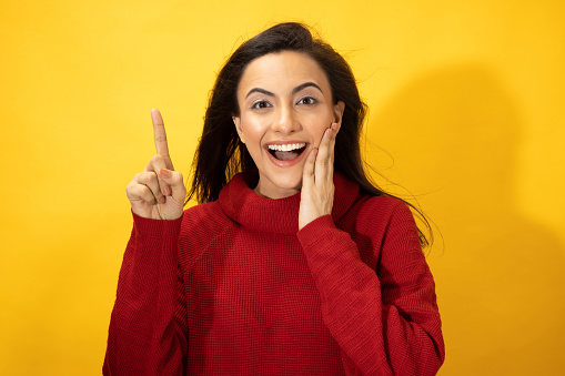 Photo of young women in winter wear standing on yellow background